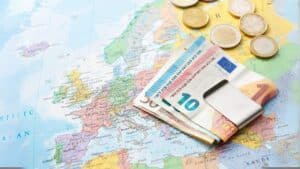 Európske eurobankovky a mince na mape Európy – symbolizujú príspevok zorgtoeslag, ktorý štát Holandsko vypláca mesačne na zdravotné poistenie.